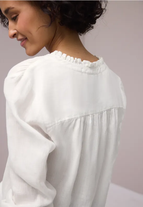 Zijaanzicht van een vrouw met een witte blouse en gekruld kort haar