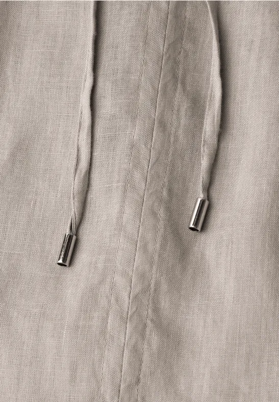 Close-up van beige stof met twee koorden en metalen uiteinden.