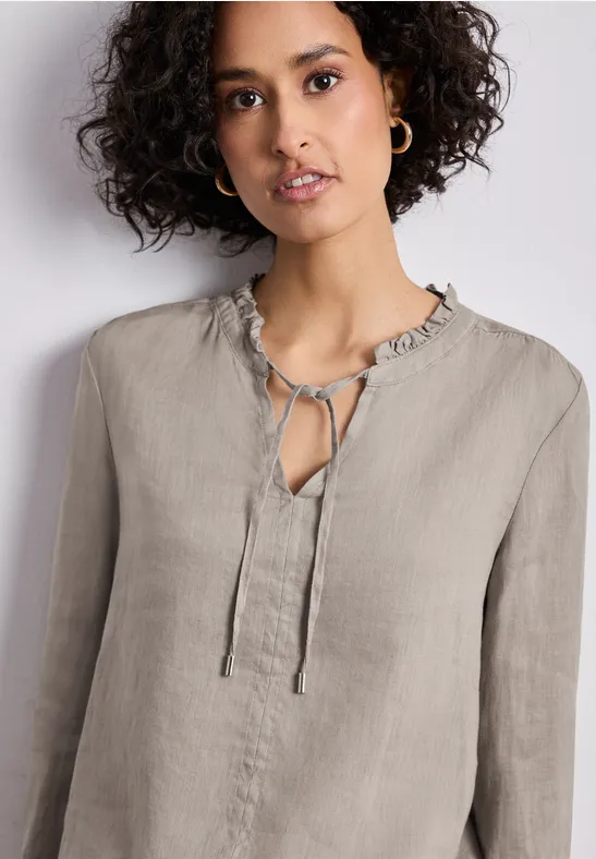 Linnen blouse in lichtgrijs met ruches aan de kraag, striksluiting bij de hals en lange mouwen.