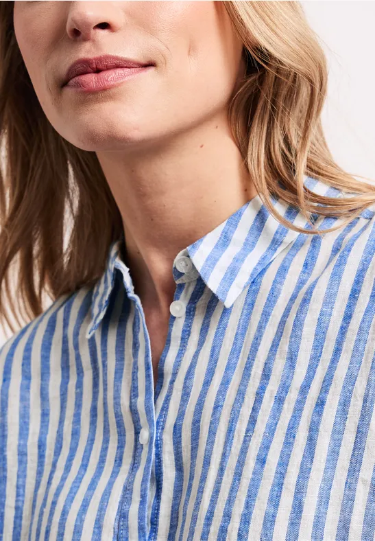 Close-up van een vrouw in een blauw-wit gestreept linnen overhemd met open kraag.