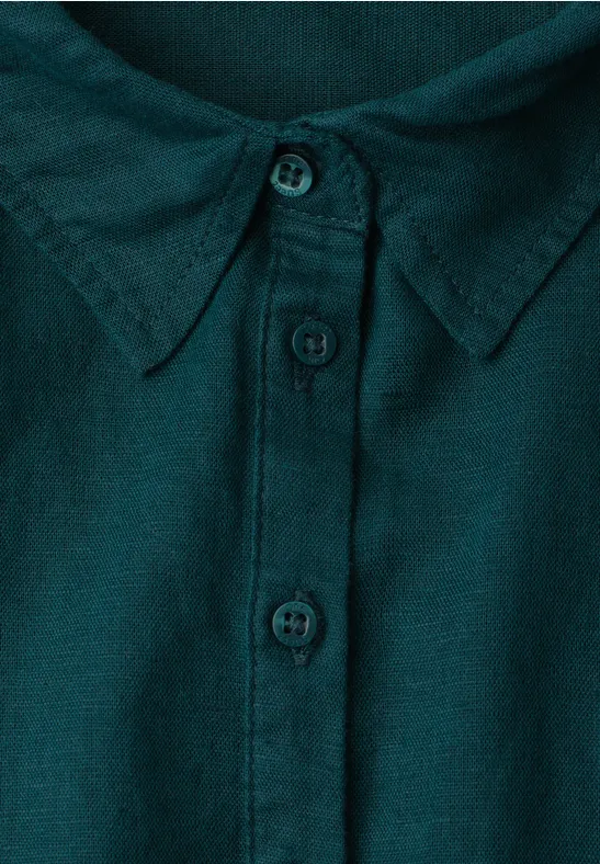 Close-up van de kraag van een donkergroen overhemd met knoopsluiting en drie zichtbare knopen.