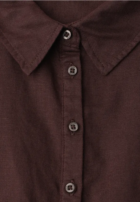Gros plan d'une chemise marron foncé à col et patte de boutonnage.
