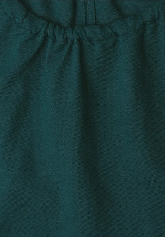 Nahaufnahme eines dunkelgrünen, elastisch gerafften Stoffs mit Naht und feiner Textur.