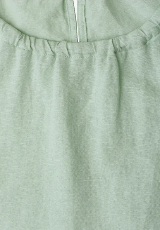 Nahaufnahme eines hellgrünen Leinenoberteils mit Raffung am Ausschnitt und Reißverschluss