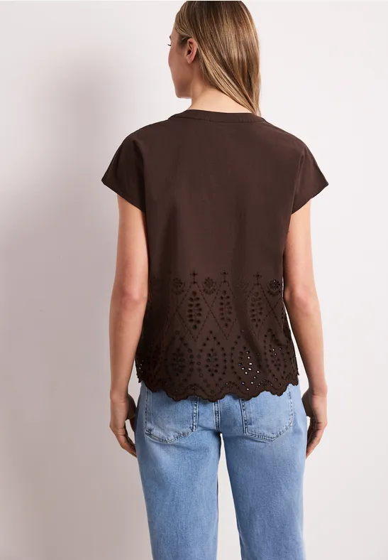 Femme vue de dos en t-shirt marron à ourlet découpé et jeans bleus.