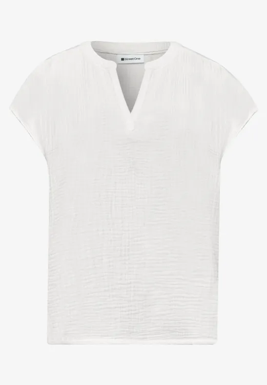 Witte, kortermelige damestop van licht gestructureerd katoen met V-hals.