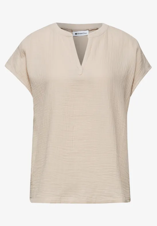 Beige dames top met korte mouwen, losse pasvorm en kleine V-hals.