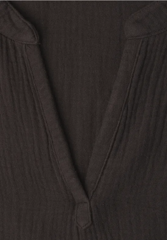 Gros plan d'un col en V côtelé de couleur brun foncé sur un haut.