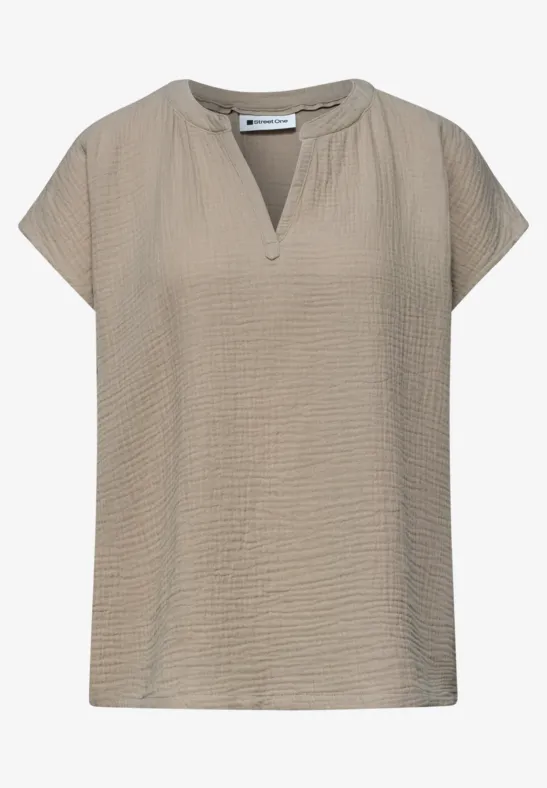 Beige damesblouse met gestructureerde stof, korte mouwen en een kleine V-hals.