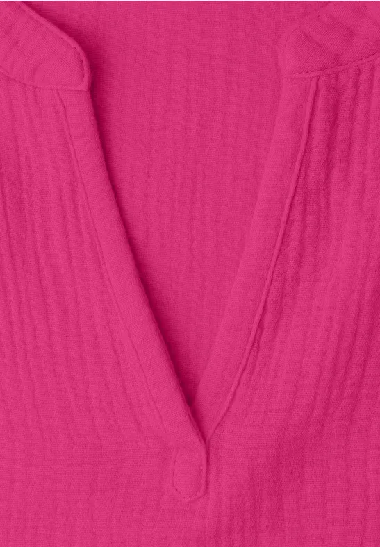 Nahaufnahme eines pinken V-Ausschnitt-Oberteils aus strukturiertem Stoff.