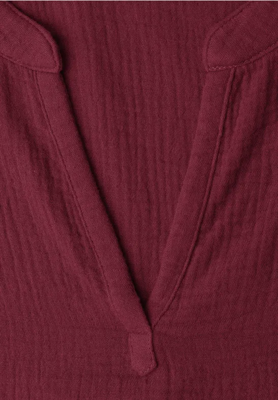 Detailaufnahme eines dunkelroten V-Ausschnitt-Shirts aus strukturiertem Stoff.