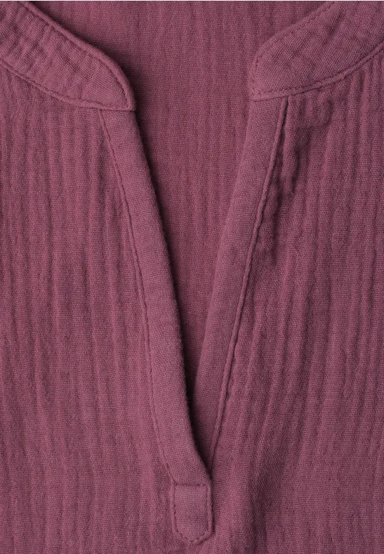 Gros plan d’un haut bordeaux en coton texturé avec encolure en V et col mao.