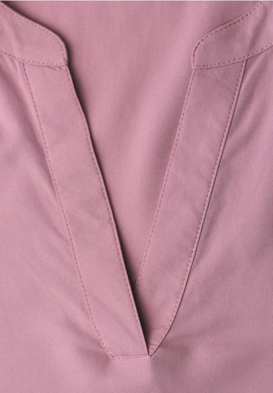 Nahaufnahme eines rosa V-Ausschnitts aus Stoff mit sichtbaren Nähten und feiner Textur.