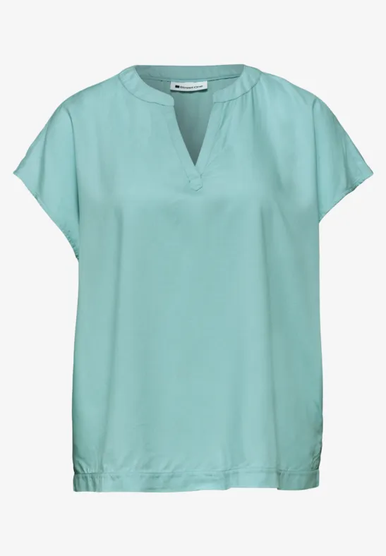 Blouse vert menthe à manches courtes, encolure en V et coupe ample.