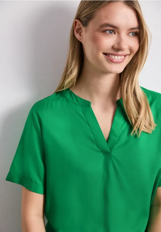 Person trägt grüne Kurzarmbluse mit V-Ausschnitt.