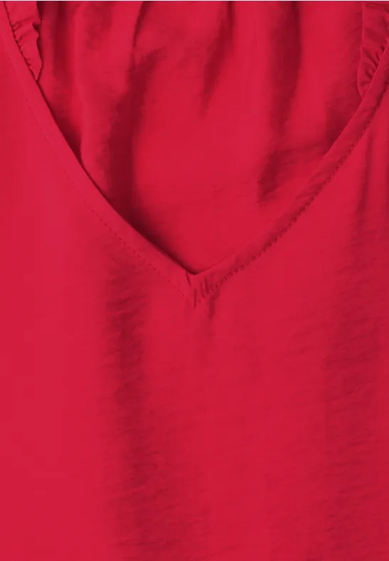 Ein rotes V-förmiges Oberteil aus glattem Stoff.