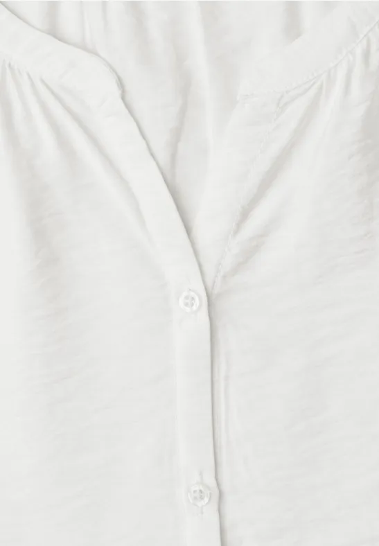 Nahaufnahme eines weißen T-Shirts mit V-Ausschnitt und zwei weißen Knöpfen.