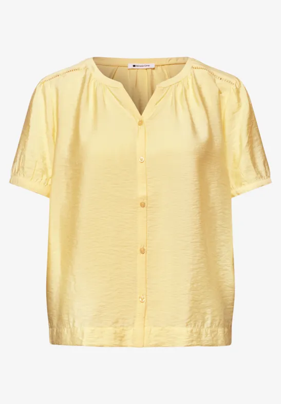 Leichte gelbe Kurzarm-Bluse mit Knopfleiste und dezent strukturierter Oberfläche.