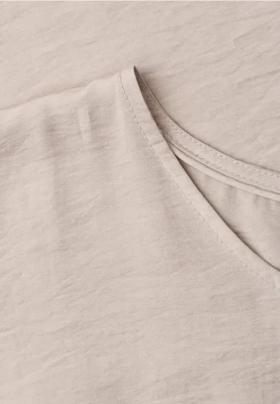 Close-up van een lichtbeige T-shirt met V-hals