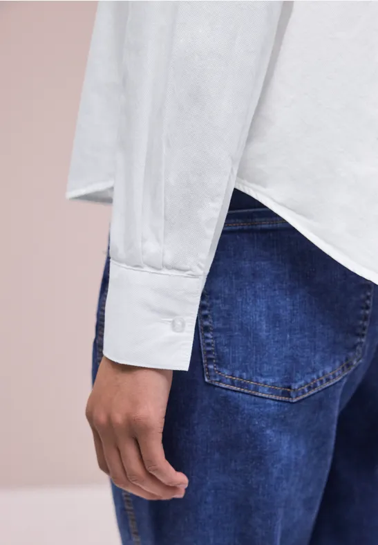 Vue latérale d’une personne en chemise blanche à manches longues et jean bleu.