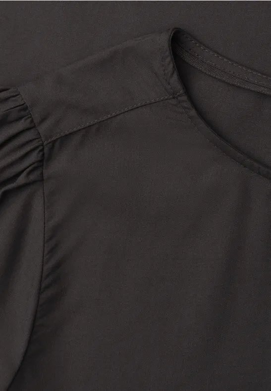 T-shirt noir à encolure ronde avec fronces discrètes aux épaules.