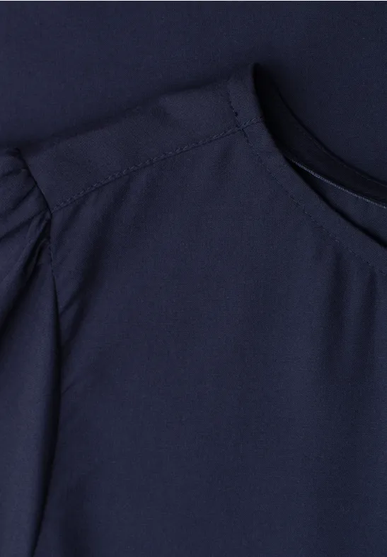 Close-up van een donkerblauw topje met ronde hals en opvallende schoudernaden.