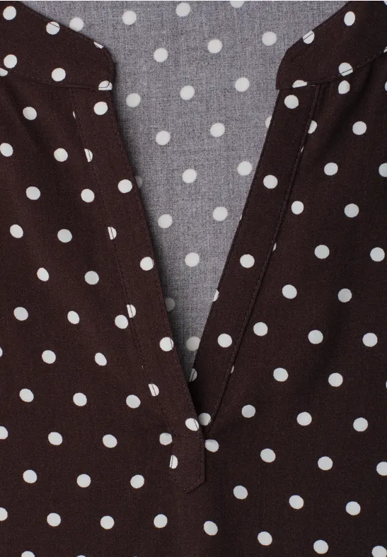 Haut marron à pois blancs avec décolleté en V.