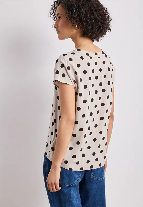 Femme vue de dos portant un t-shirt à pois et un jean