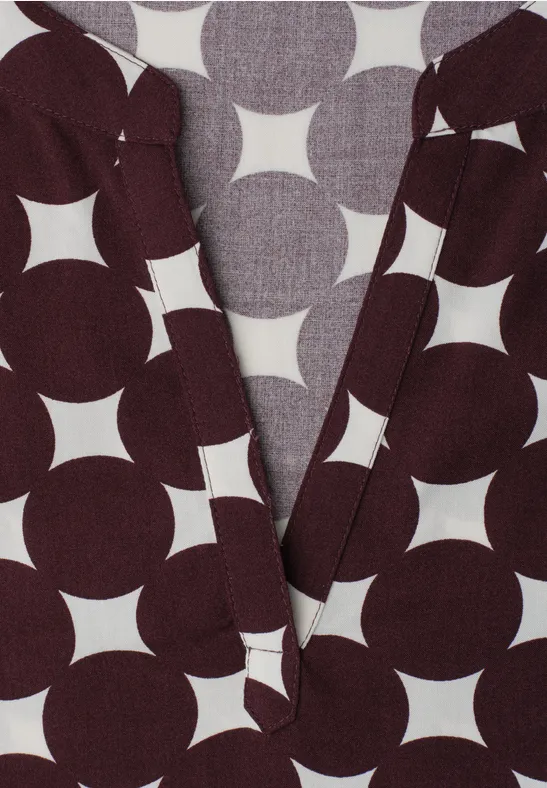 Vêtement sombre à motif géométrique blanc de cercles et étoiles, décolleté en V