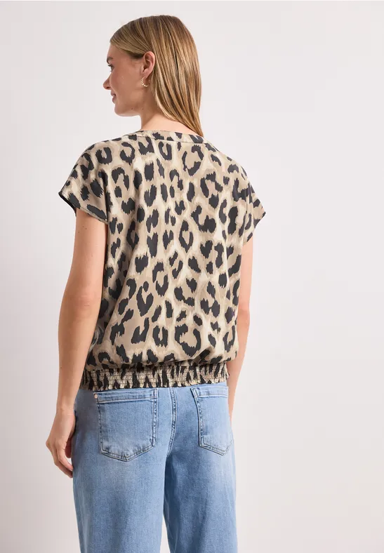 Frau von hinten in Jeans und kurzärmeligem Oberteil mit Leopardenmuster.