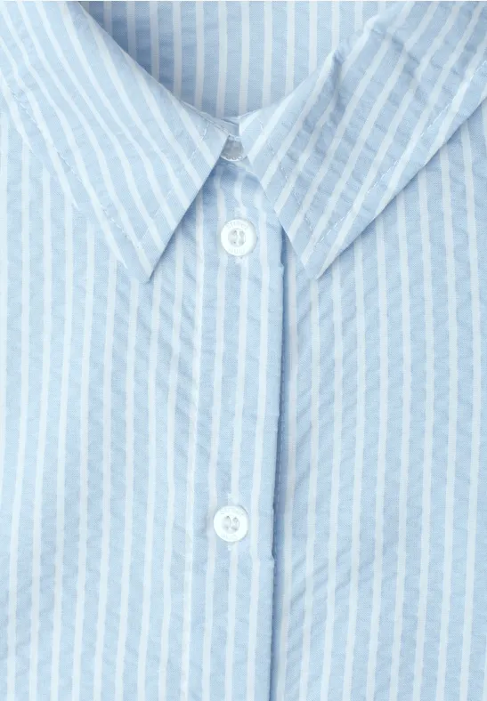 Lichtblauw overhemd met witte strepen, klassieke kraag en twee zichtbare knopen.
