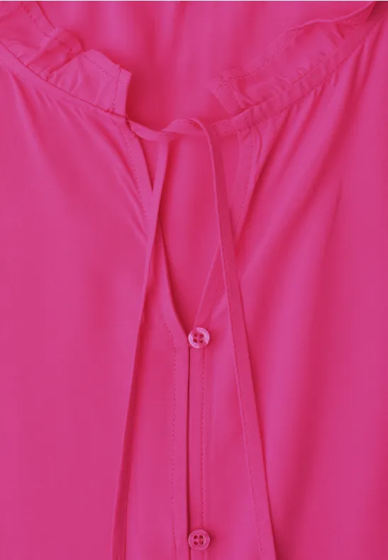Nahaufnahme einer pinken Bluse mit Rundhalsausschnitt und Knopfleiste.