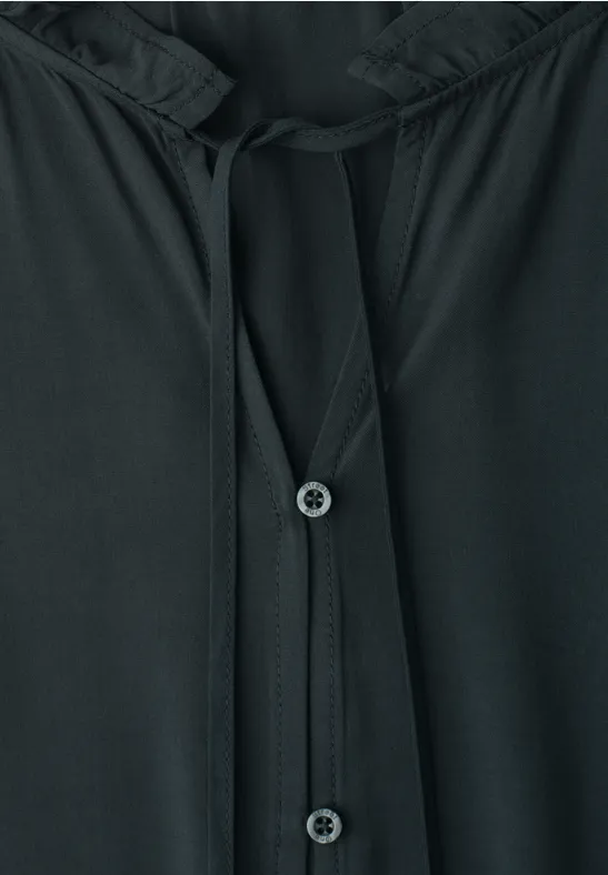 Schwarzes Oberteil mit Knopfleiste und Kordeln am Halsausschnitt.