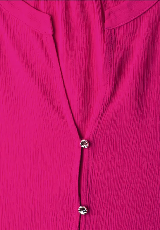 Fuchsia blouse met geribbelde textuur en twee fonkelende knopen middenvoor.