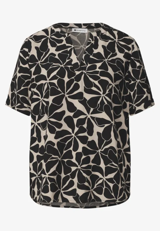 Blouse noire à motif floral beige, col en V et manches courtes.