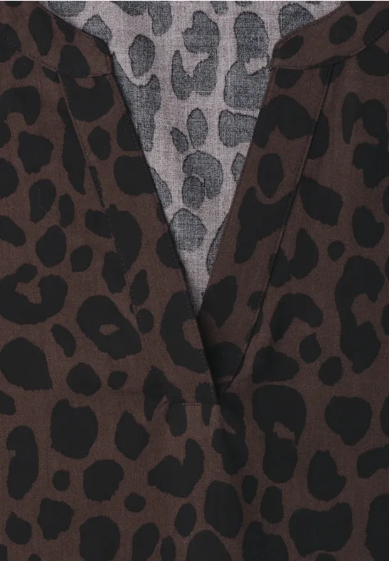 Nahaufnahme eines Kleidungsstücks mit braun-schwarzem Leopardenmuster und grauem Unterstoff mit schwarzen Flecken.