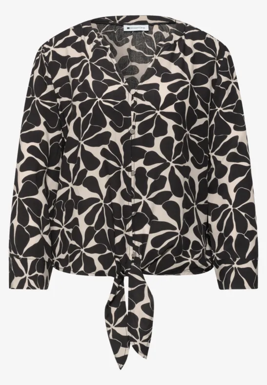 Zwart-witte blouse met groot bloemmotief en strik aan de zoom.