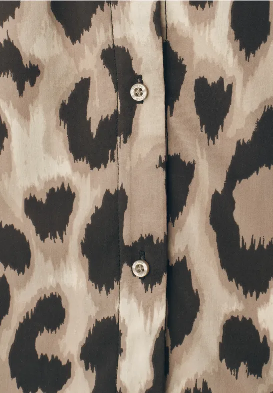 Beige Bluse mit schwarzen, herzförmigen Flecken im Leopardenstil und zwei runden Knöpfen.
