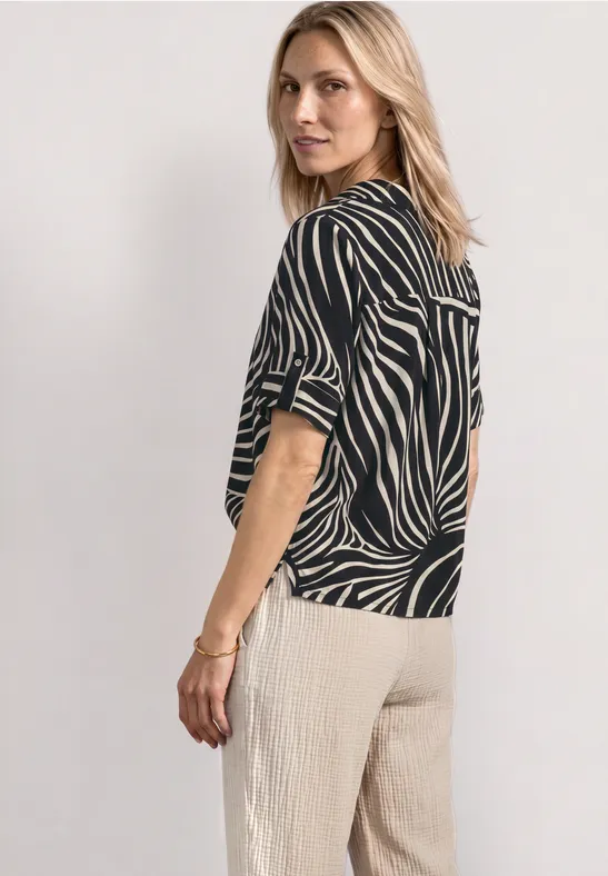 Femme de profil portant un haut zébré noir et blanc et un pantalon ample beige