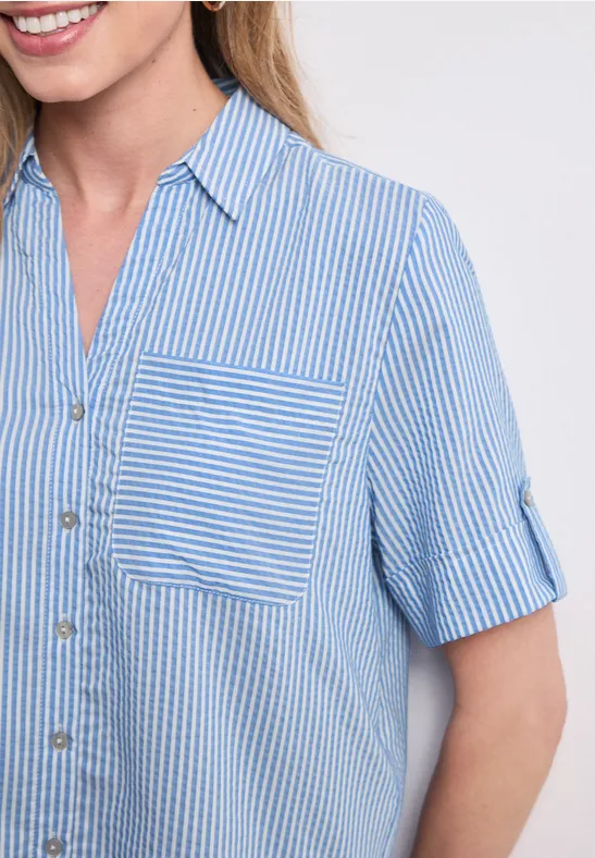 Close-up van een vrouw in blauw-wit gestreept overhemd met borstzak.