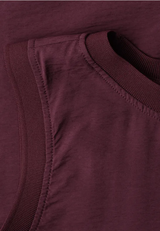 Afbeelding van een close-up van een bordeauxrood mouwloos katoenen shirt.