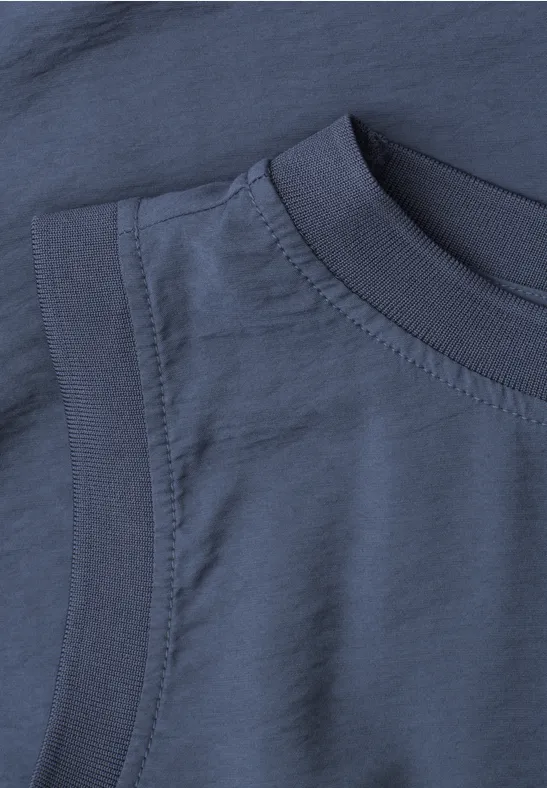 Nahaufnahme eines dunkelblauen T-Shirt-Ausschnitts mit sichtbaren Nähten und strukturiertem Stoff.