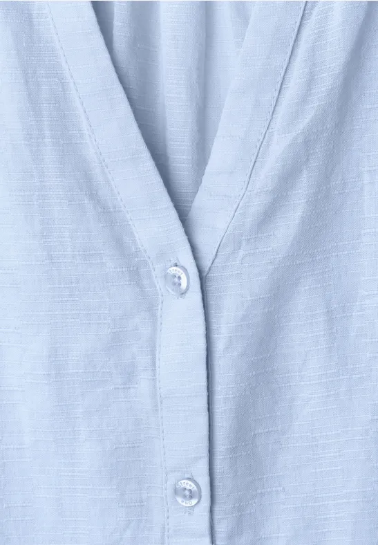 Close-up van een lichtblauw overhemd met eenvoudige knoopsluiting.