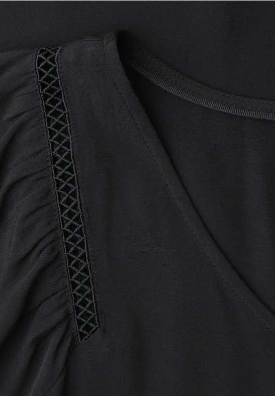 Haut noir sans manches, détail froncé et motif triangulaire sur la couture d'épaule.