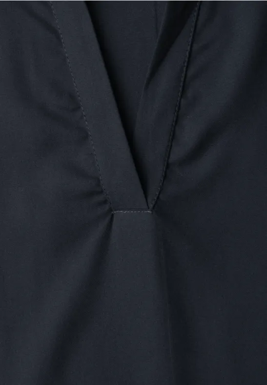 Détail d'un vêtement sombre avec une ouverture en V et une couture décorative.