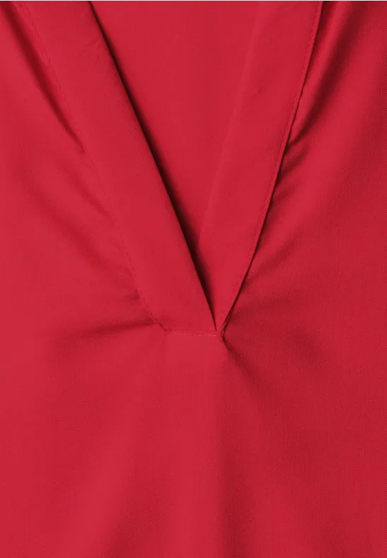 Roter Stoff mit V-förmigem Ausschnitt und feinen Falten.