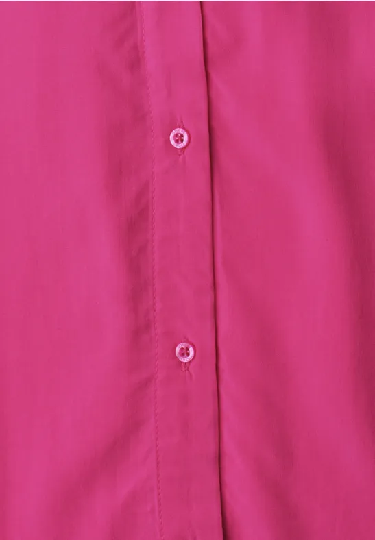 Nahaufnahme einer pinken Bluse mit weißen Knöpfen und Knopfleiste.
