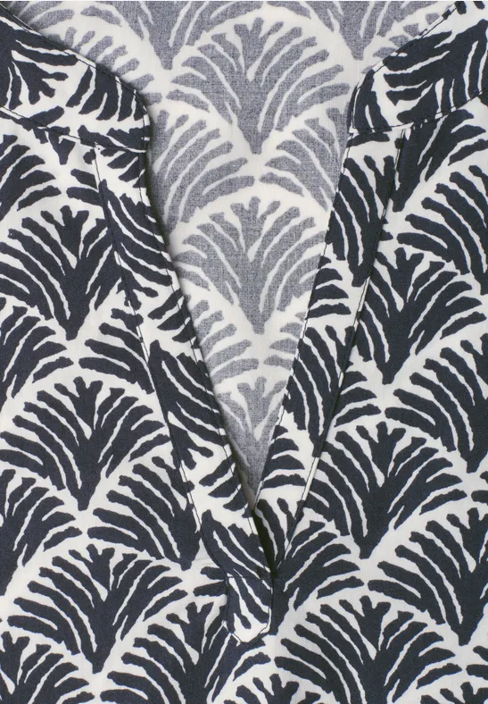 Nahaufnahme eines Stoffes mit schwarz-grauem Blattmuster auf hellbeigem Grund.