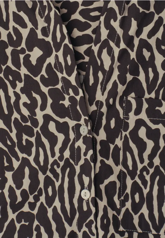 Close-up van een beige blouse met zwart luipaardprint en witte knopen.