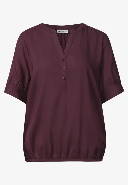 Damesblouse in donker paarstint, korte mouwen, V-hals met knopen en elastische zoom.